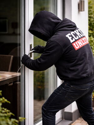 Mit Kapuze vermummter Einbrecher versucht eine Terassentür zu öffnen